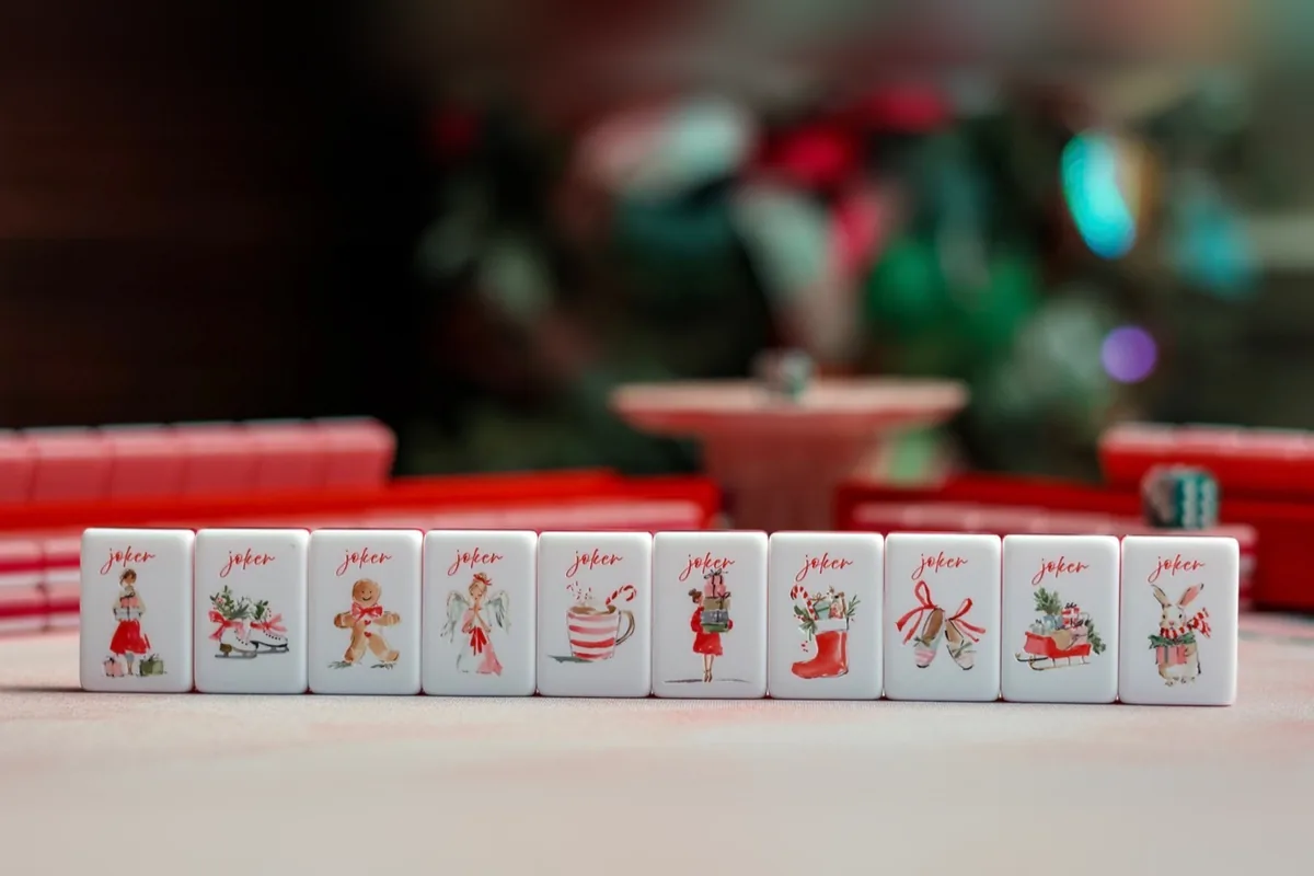 Ten Noel Collection joker tiles in a row: a girl with gifts, ice skates, a gingerbread man, an angel, cocoa, a stocking, ballet slippers, a sleigh and a bunny.