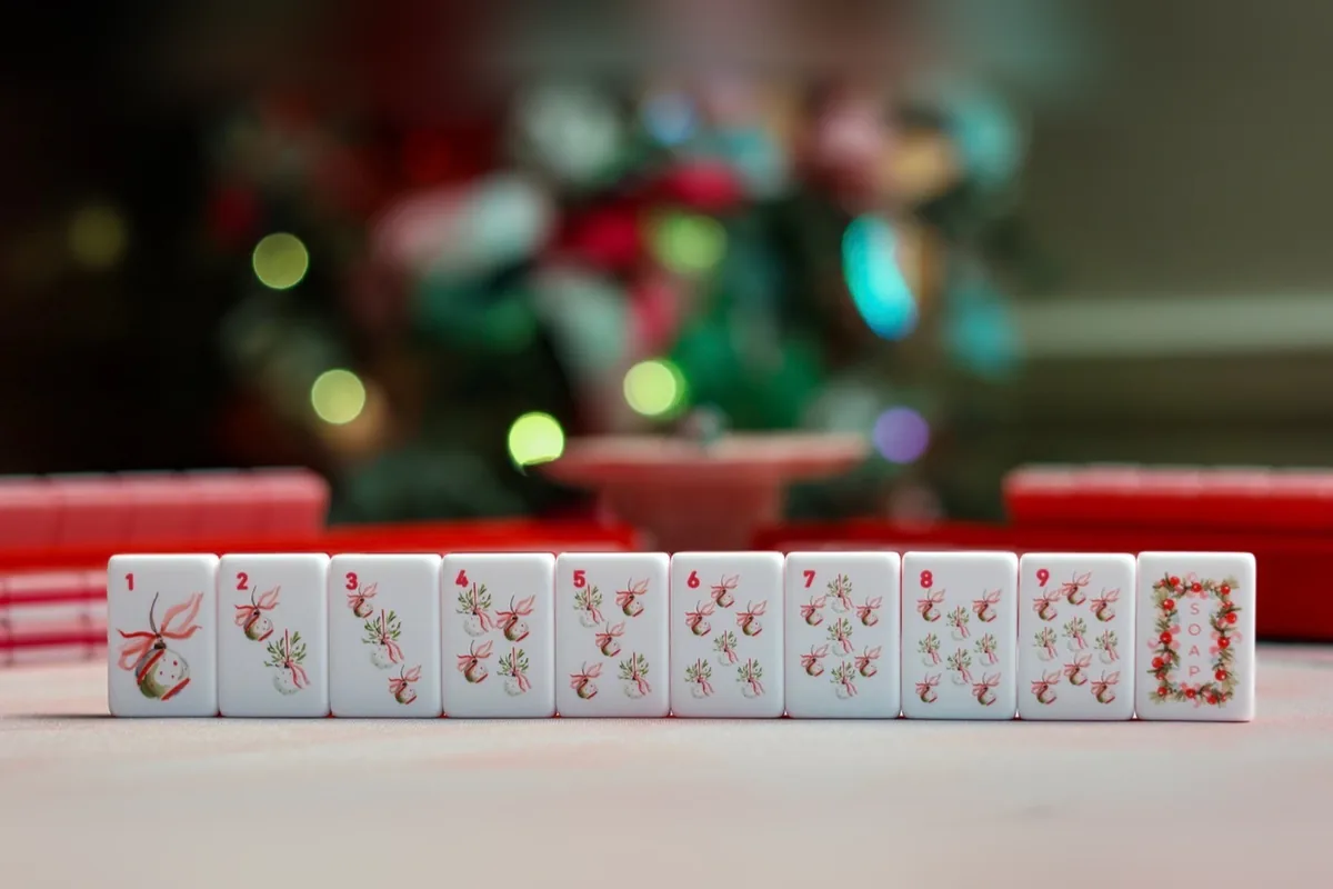A row of Noel Collection suit tiles numbered 1 to 9 in ribboned Christmas ornaments, finished with a “Soap” tile framed in a garland of red berries.