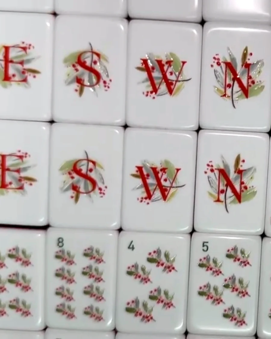 Noel Collection wind tiles — east, south, west and north in red serif letters over painted holly, berries and gilded leaves.